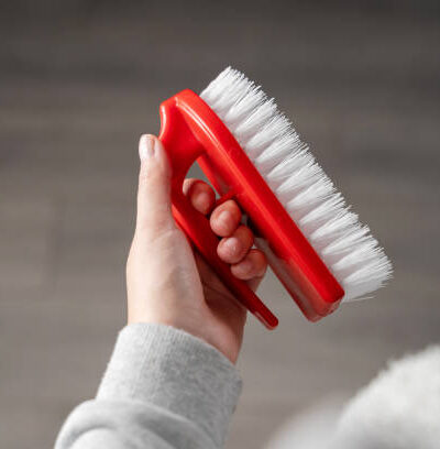 Close up top view on hand of unknown woman holding red scrub cleaning brush