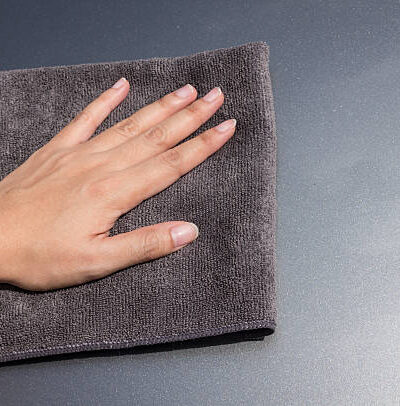 Hand with microfiber cloth cleaning car
